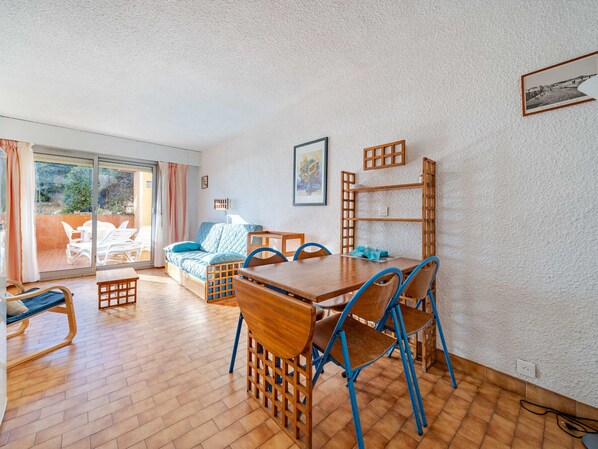A room with a wooden dining table, blue chairs, a sofa, and a balcony with white chairs. - Studio for 4, sea view, Wi-Fi included (Roquebrune-Cap-Martin)