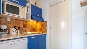 A kitchen with blue cabinets, a white microwave, a coffee maker, and a dishwasher. - Studio for 4 with Unlimited Wi-Fi, Sea View (Roquebrune-Cap-Martin)