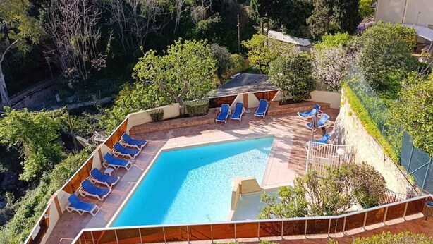 A swimming pool with sun loungers, surrounded by greenery and overlooking a body of water. - Studio for 4 with Unlimited Wi-Fi, Sea View (Roquebrune-Cap-Martin)