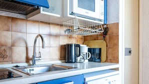 A compact kitchen with blue cabinets, a microwave, a coffee maker, and a dish rack. - Studio for 4, sea view balcony, Wi-Fi included (Roquebrune-Cap-Martin)
