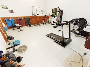 A gym with various exercise equipment including a treadmill, weight machines, and free weights.