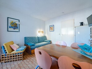 A cozy room with a wooden dining table, a blue sofa, and a wooden chair with a cut-out backrest.
