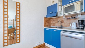 A compact kitchen with blue cabinets, a microwave, a coffee maker, and a dishwasher.