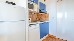 A compact kitchen with a white refrigerator, a microwave, and blue cabinets. - Studio for 4 with Wi-Fi, sea view (Roquebrune-Cap-Martin)