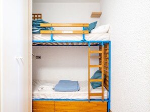 A bunk bed with a ladder, a small shelf, and a white door.