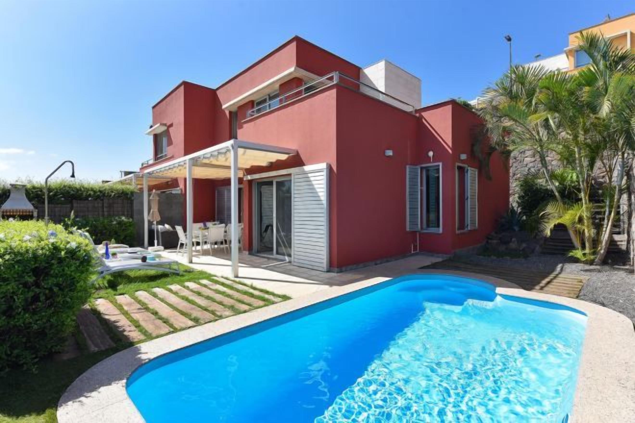 Una casa moderna a due piani con piscina, veranda coperta e giardino.