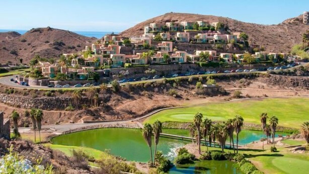 A resort with multiple buildings, a golf course, and a large body of water.