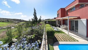 A modern house with a swimming pool, surrounded by a well-maintained garden and a scenic view of the countryside.