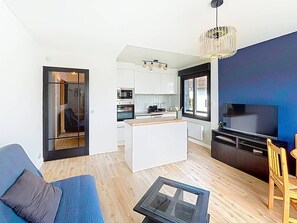 A modern living space with a kitchen, dining area, and entertainment unit.