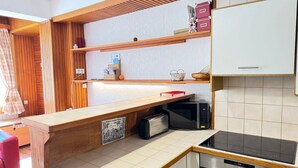 A compact kitchen with wooden countertops, a built-in microwave, a stove, and a small refrigerator.