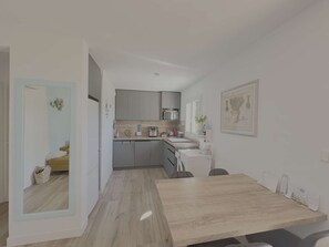 Una cucina moderna con mobili grigi, un tavolo da pranzo in legno e un piccolo angolo relax.