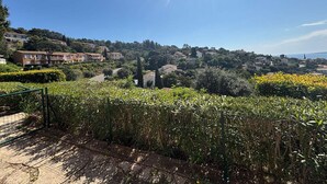 A residential area with houses on a hillside, a clear sky, and a view of the sea.