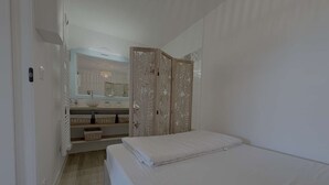 A bedroom with a bed, a vanity with a mirror, and a wardrobe.