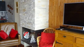 A living room with a leather sofa, a wooden cabinet, and a television. - Les Gets: Duplex Apartment 3 Rooms 7 People, Wifi, Garage (Les Gets)