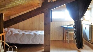A small, cozy attic bedroom with a single bed, a chair, and a desk. - Les Gets: Duplex Apartment 3 Rooms 7 People, Wifi, Garage (Les Gets)