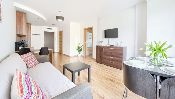 Ein modernes Wohnzimmer mit einer Couch, einem Couchtisch und einem Essbereich mit Tisch für zwei Personen.