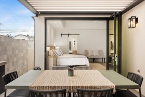 A modern hotel room with a large bed, a sofa, a dining table with chairs, and a sliding glass door leading to a balcony. - Pristine and Central 4-bedroom home perfect for elegant entertaining/relaxation (Coronado)
