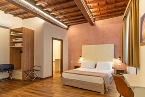 A bedroom with a bed, bedside tables, a desk, a chair, a wardrobe, and a ceiling with exposed beams. - Cennini 6 (Florence)