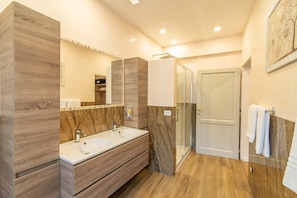 A modern bathroom with a wooden vanity, a large mirror, a glass shower enclosure, and a white towel hanging on the wall. - Cennini 6 (Florence)