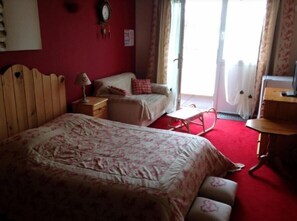 Un dormitorio con una cama de madera, una mesita de noche de madera, una mecedora y una pequeña mesa.