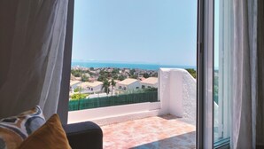 A balcony with a view of a coastal town and the sea.