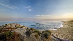 A coastal landscape with a sandy beach, rocky outcrops, and the ocean.