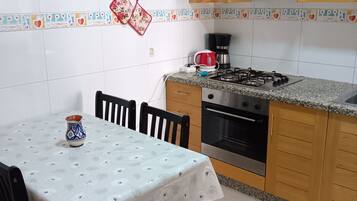 A kitchen with a dining table, chairs, a stove, oven, and cabinets.