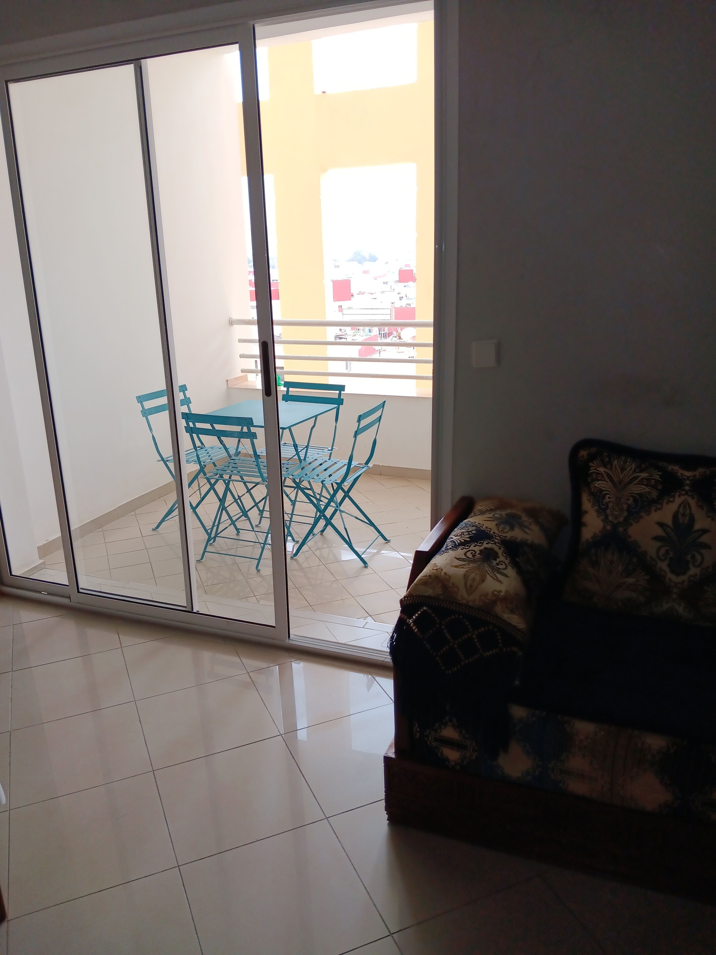 Un salon doté d’une porte-fenêtre coulissante donnant sur un balcon équipé d’une table et de chaises.