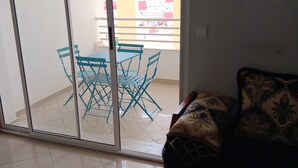 Een woonkamer met een schuifdeur die uitkomt op een balkon met een tafel en stoelen.