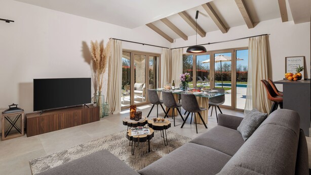 A modern living room with a flat-screen TV, grey sofa, dining table with chairs, and a view of the outdoors. - Sun  Spalato Villa Oblica (Jadruhi)
