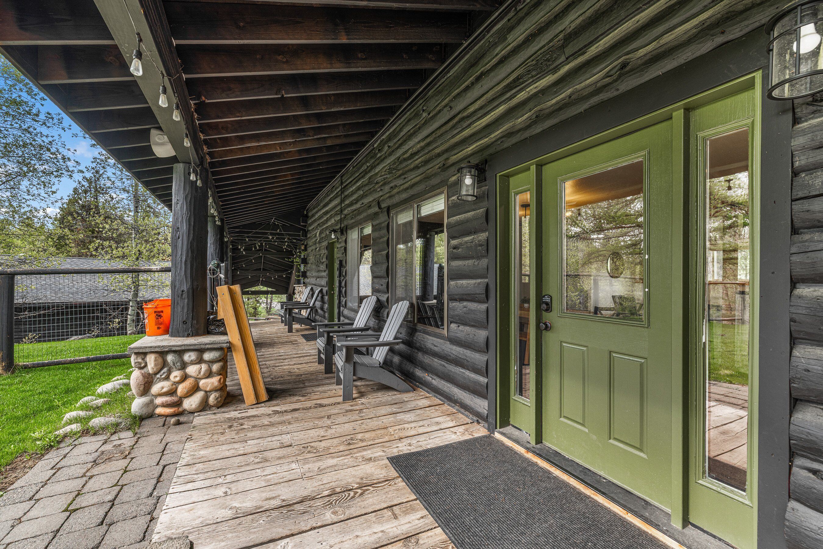 A wooden cabin with a porch, outdoor seating, and a green door.