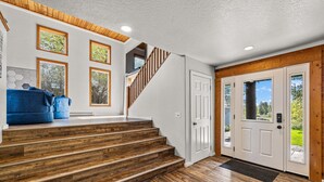 A staircase with wooden steps leading to a landing, a white door with a window, and a blue bench. - Black Fork Lodge - Beautiful log home on 2.5 acres with trailer parking and panoramic views (McCall)