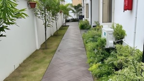 A narrow pathway flanked by potted plants and a white wall. - Diaggello Homes Apartment (Ibeju)