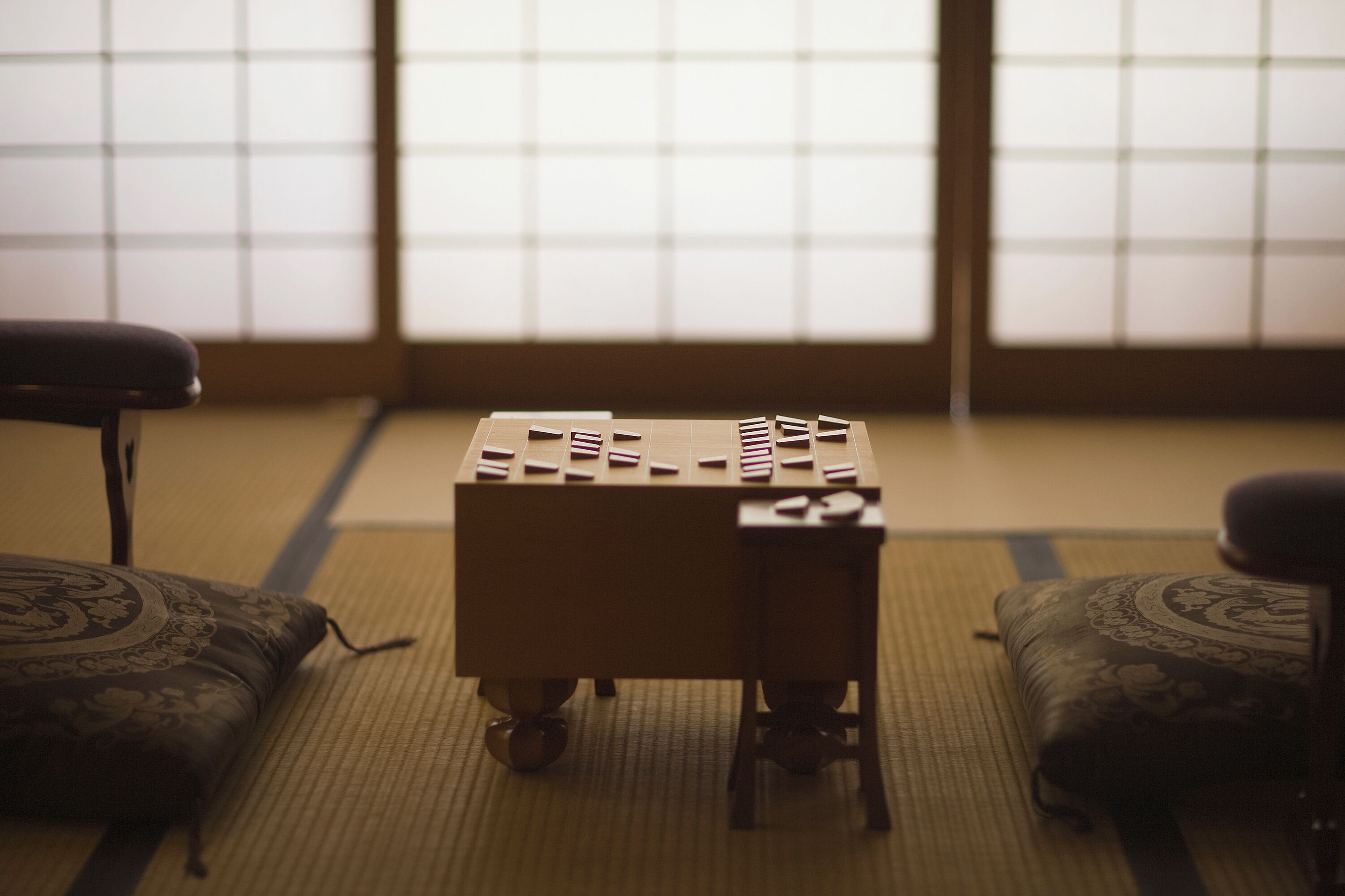 Une pièce avec un sol recouvert de tatamis, une table en tatami et des coussins.