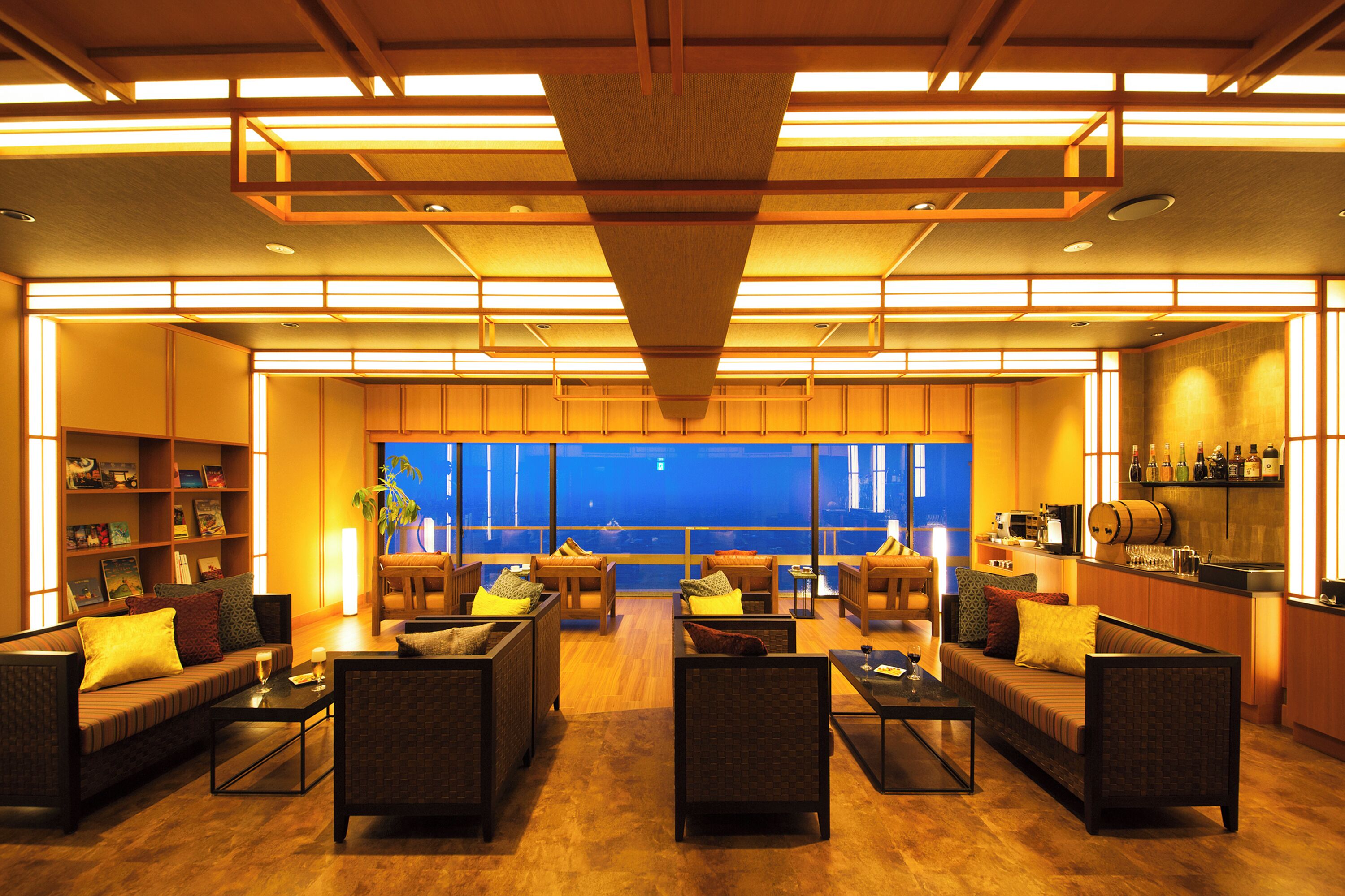 A spacious lobby with a seating area, a bar, and a view of the cityscape.