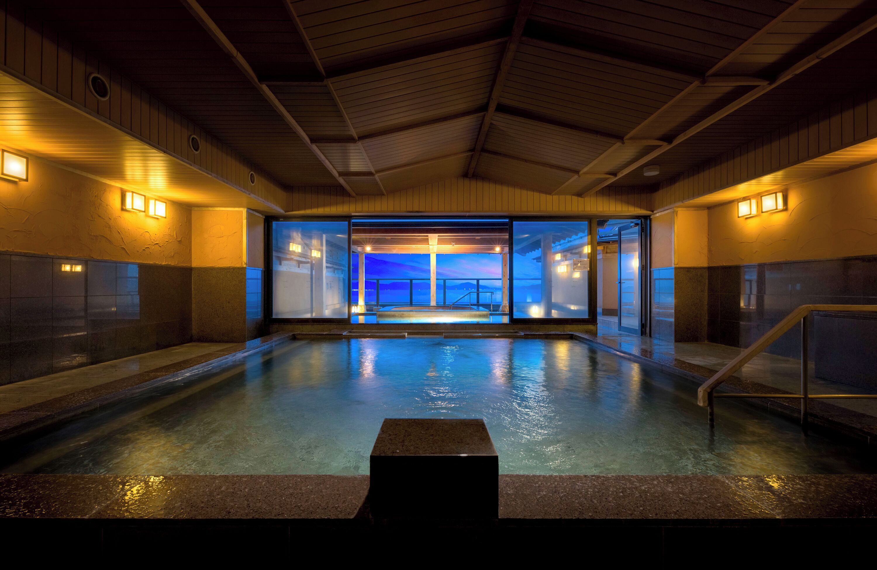 An indoor swimming pool with a view of the sky through a glass wall.