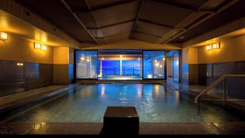 An indoor swimming pool with a view of the sky through a glass wall.