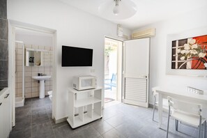 Een moderne badkamer met een wastafel, toilet en een flatscreen televisie aan de muur.