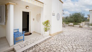 Un bâtiment à la façade blanche, avec un banc bleu et un pot de fleurs.