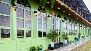 A green building with multiple windows and outdoor lighting fixtures. - Chitralekha Boutique Resort (Dehradun)