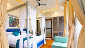 A four-poster bed with white and teal bedding, a teal sofa, and a ceiling fan. - Chitralekha Boutique Resort (Dehradun)
