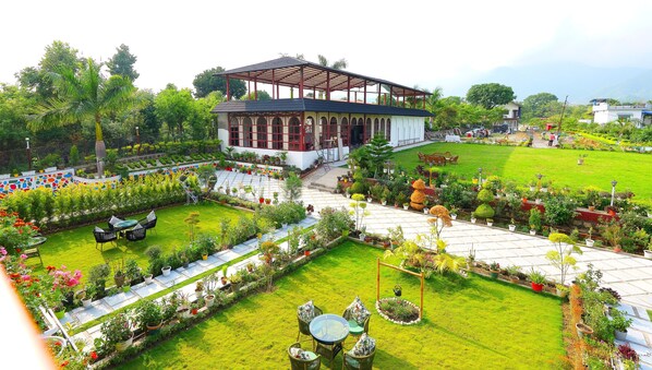 A garden with a gazebo, a lawn, and a variety of potted plants.