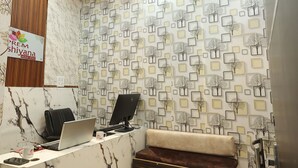 A reception area with a marble counter, two black office chairs, a laptop, a desktop computer, and a sofa. - Prem Aashiyana Home Stay (Agra)