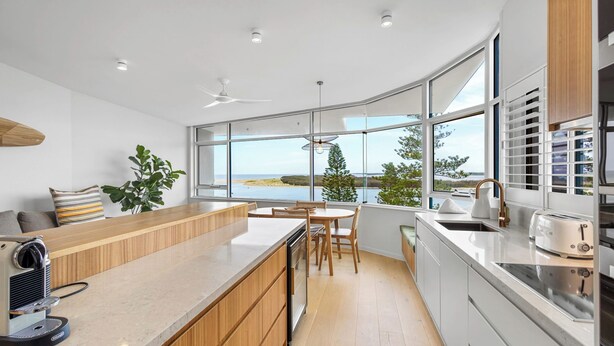 Una cocina moderna con un amplio ventanal, armarios de madera y una isla integrada.