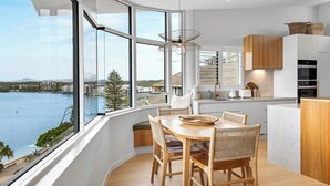 Una cocina moderna con ventanas amplias, muebles de madera y vista a un cuerpo de agua.