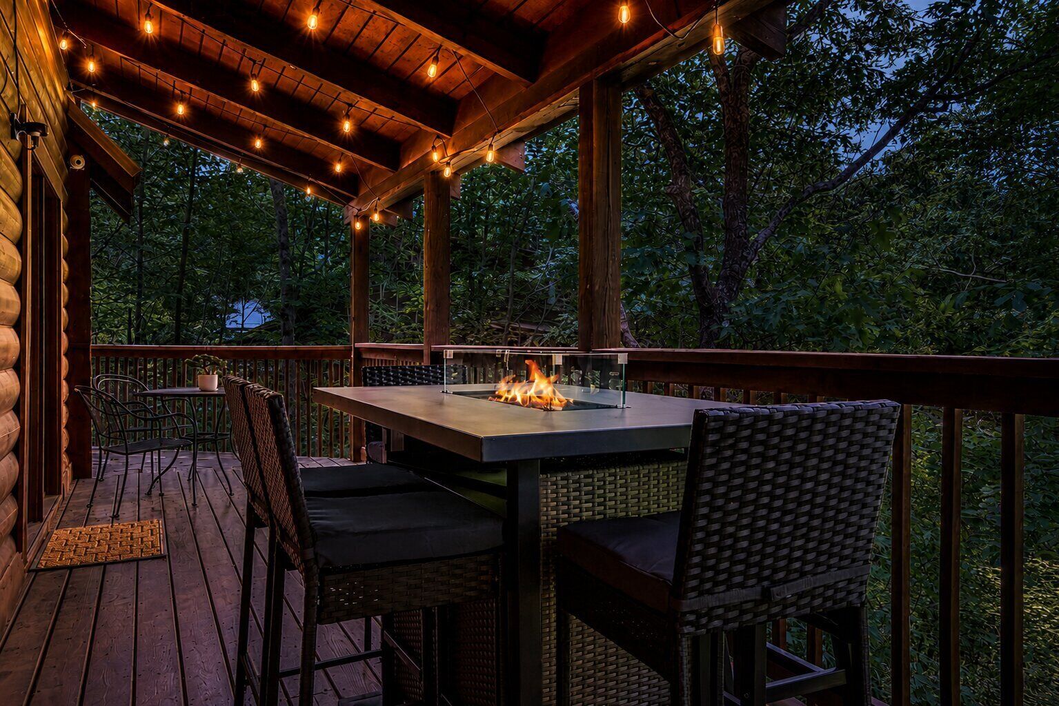 An outdoor deck with a table and chairs, a fire feature, and a wooden railing.