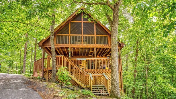 A cabin with a wooden exterior, a balcony, and a staircase leading to the entrance. - Hidden Mountain Dream, Lake View, Foosball, Hot Tub, Free Attraction Tickets!!! (Sevierville)