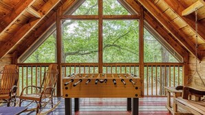 A wooden-floored room with a large window, a foosball table, and two rocking chairs. - Hidden Mountain Dream, Lake View, Foosball, Hot Tub, Free Attraction Tickets!!! (Sevierville)