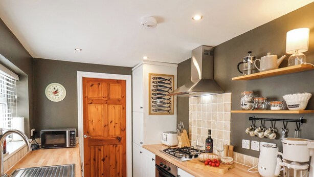 A compact kitchen with a microwave, sink, stove, and various utensils.