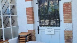A small outdoor seating area with a table and chairs, a white door with a sign, and a window with decorative iron bars. - between  carcassonne and narbonne with swimming pool (Capendu)